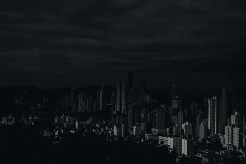 Dark and moody cityscape image showcasing skyscrapers under a cloudy sky.