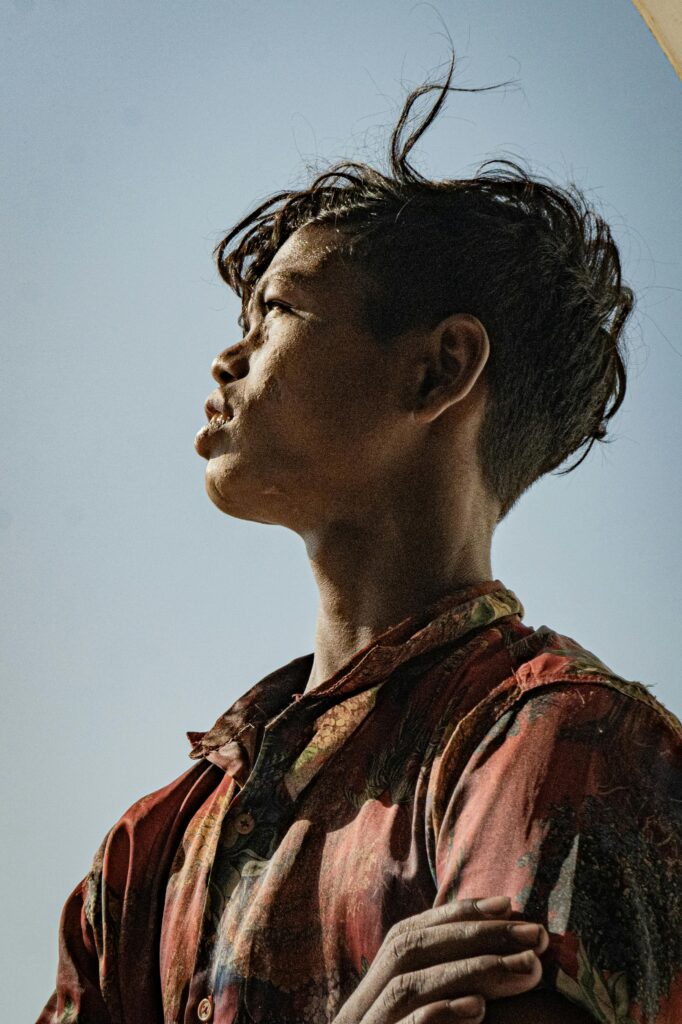 A young man gazes thoughtfully into the distance, framed by a clear blue sky.