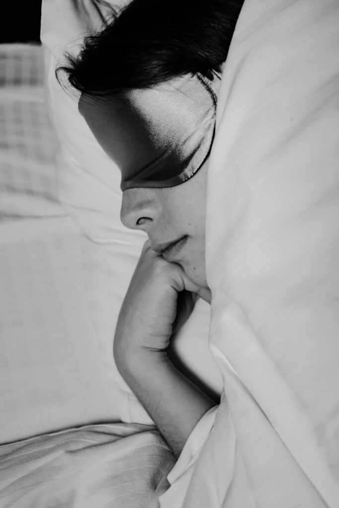 Black and white image of a woman sleeping peacefully with a sleep mask on.