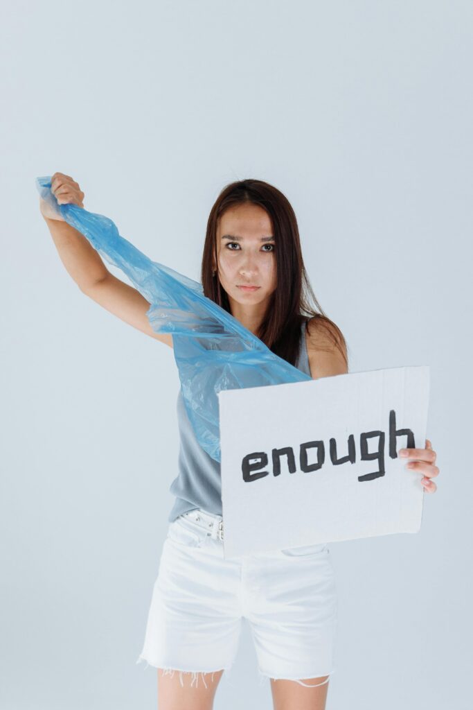 Woman holding a sign reading 'enough' in a protest against plastic pollution.