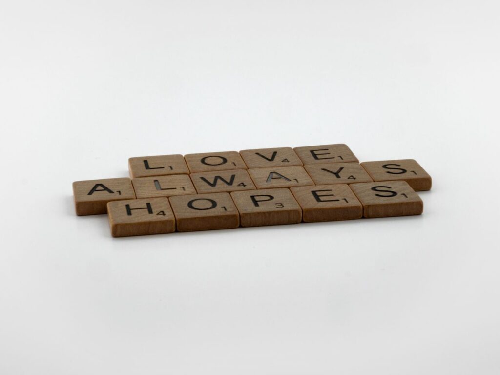 A thoughtful message spelled with Scrabble tiles on a white surface, conveying hope and love.